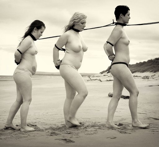 three slave women being led along a beach