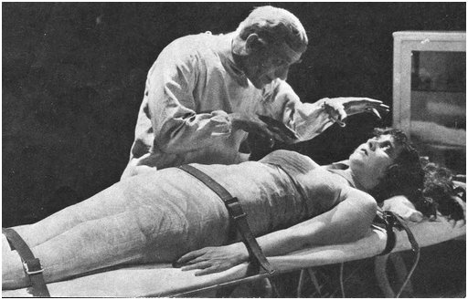 frightened woman strapped to a medical gurney