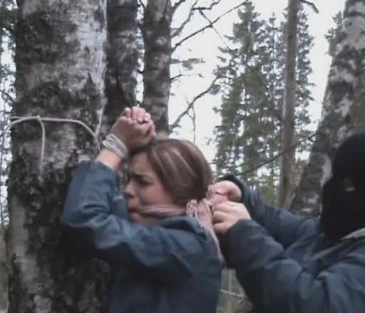 tied to a tree and gagged tightly by a hooded captor