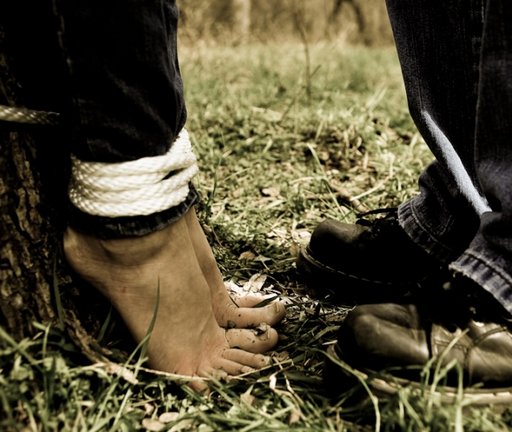 barefoot woman bound by man wearing hiking boots
