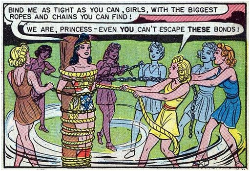 Wonder Woman's female henchwomen wind ropes and chains around her as they attempt to bind the superheroine to a sturdy pole