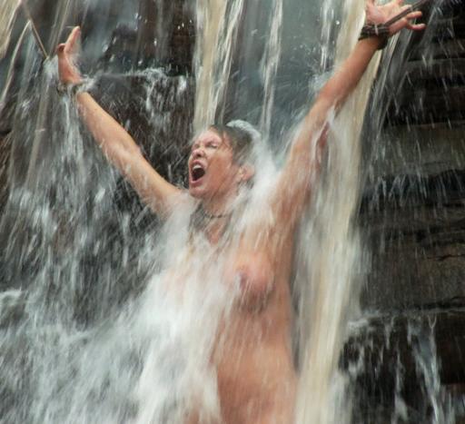 very cold girl tied in a thundering waterfall on a gray rainy day