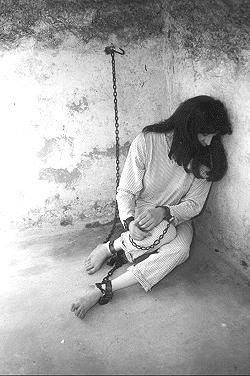 vintage photo of woman in chains in a stone jail cell