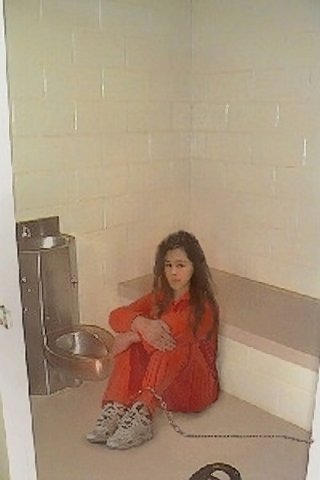 ankle chained prisoner in prison jump suit next to a prison toilet