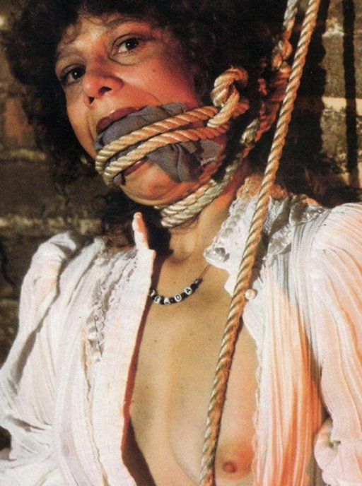 cloth gagged and roughly tied against a brick wall with course ropes