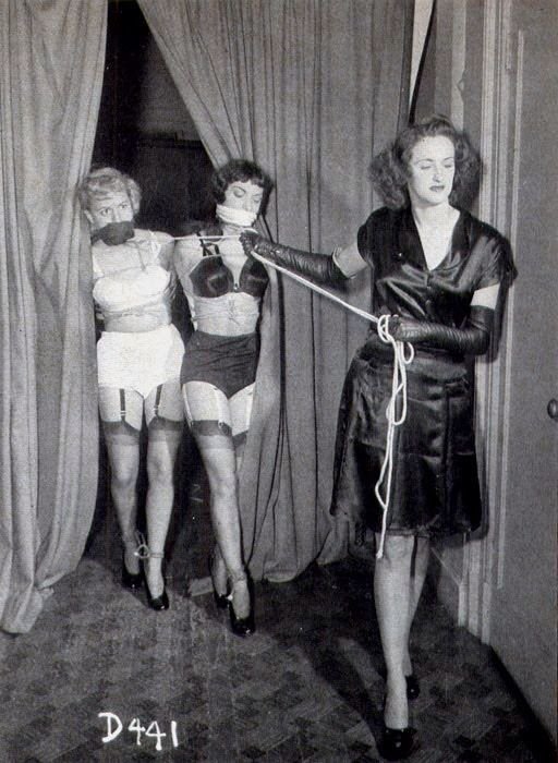 womn leads two bound and gagged women in lingerie