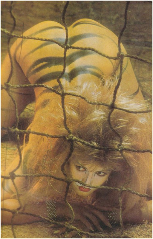 nude blonde in tiger strips and face paint struggles against a capture net