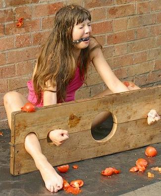 rotten tomatoes in the face for the gagged girl in the stocks