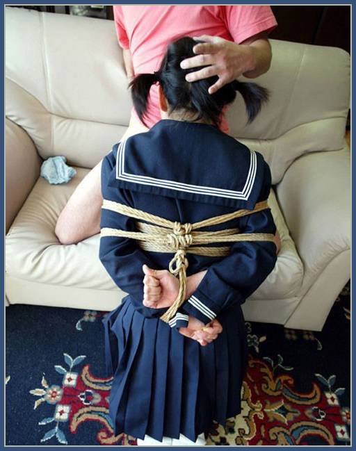 woman in japanese schoolgirl outfit giving a bondage blowjob