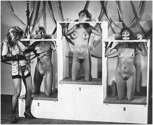three slaves pinned in a slave auction display stand