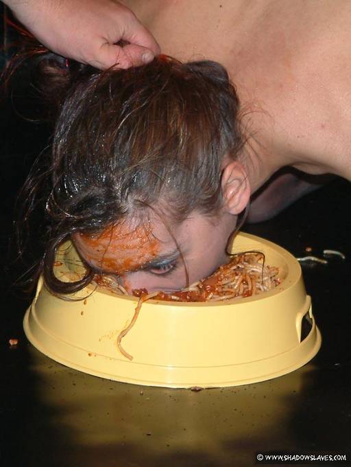 slave girl eating spaghetti out of a dog dish with her mouth and face