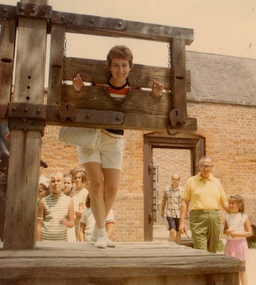 tourist mom posing in a huge wooden pillory