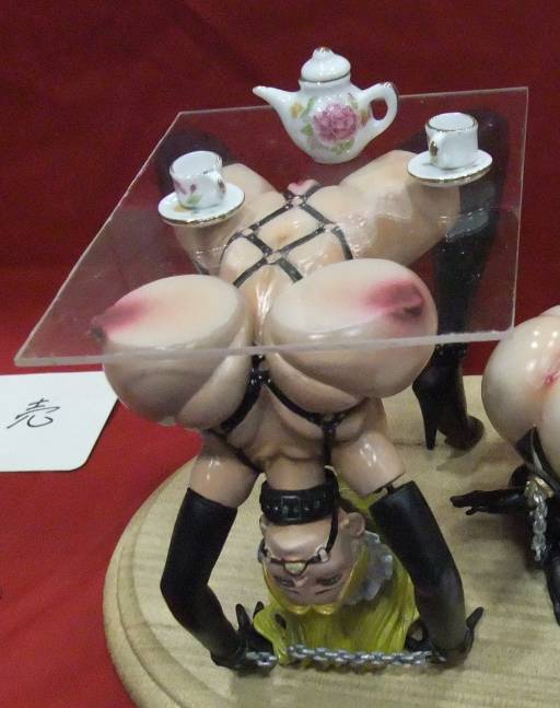 bondage figure holding up a tea party table